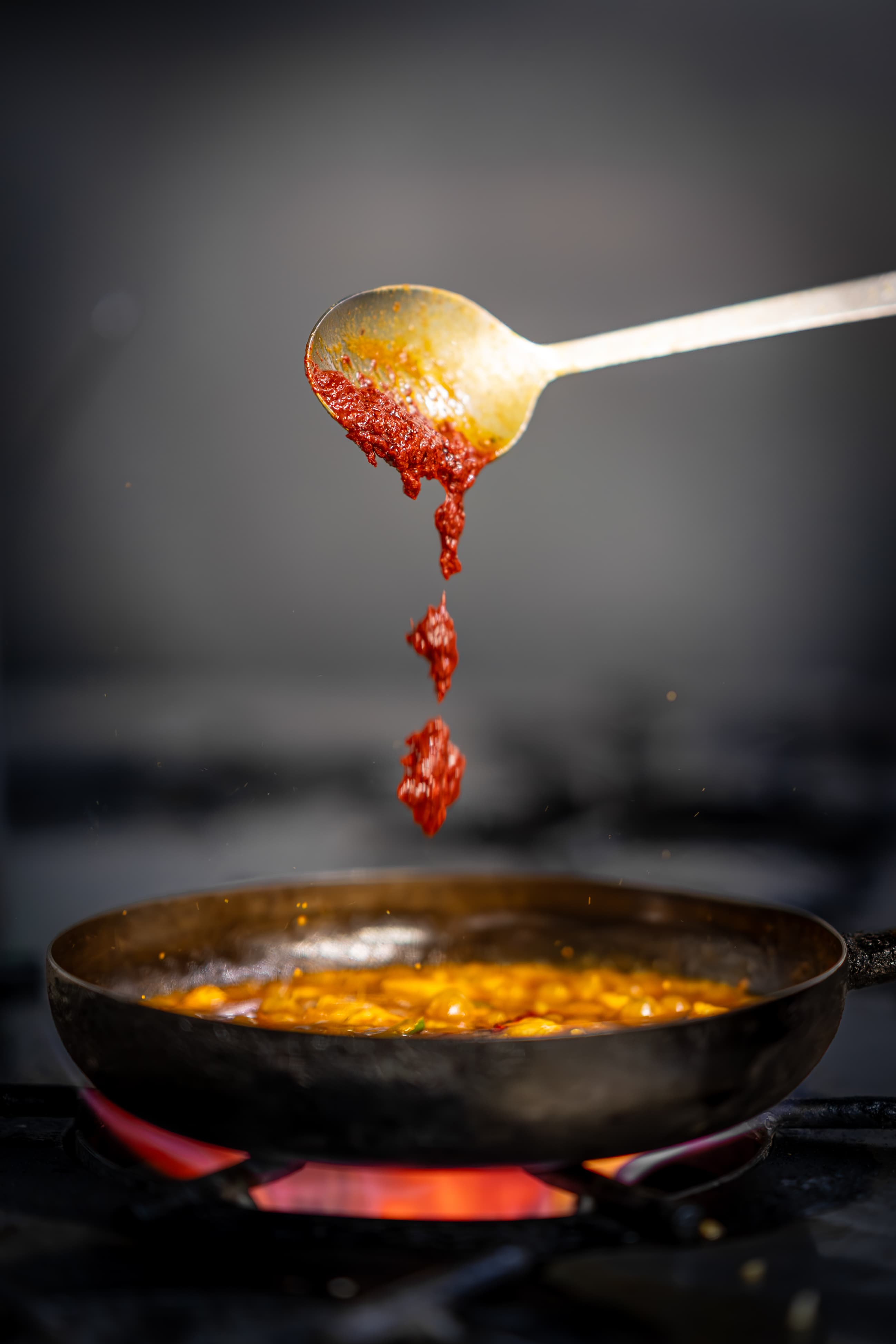 Spiced curry paste being added to a pan