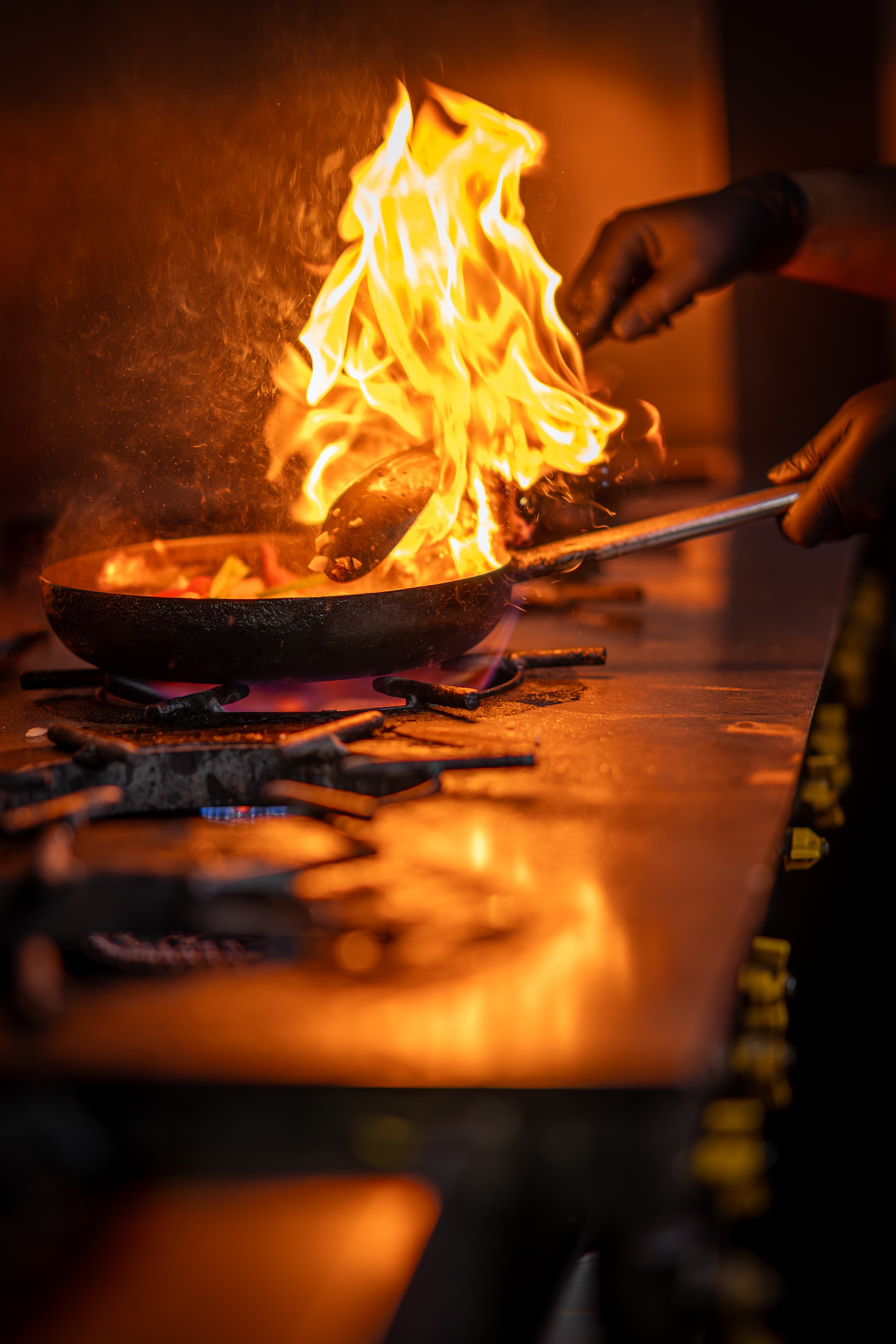 Chef flambéing peppers in a frying pan